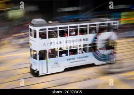 Eine Straßenbahn fährt entlang der des Voeux Road, Central, Hong Kong Island, in einer Schwenkaufnahme mit selektiven Bewegungsunschärfen aufgrund von Kamerabewegungen Stockfoto