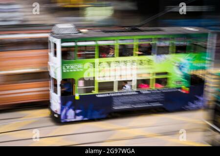 Eine Straßenbahn fährt entlang der des Voeux Road, Central, Hong Kong Island, in einer Schwenkaufnahme mit selektiven Bewegungsunschärfen aufgrund von Kamerabewegungen Stockfoto