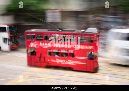 Eine Straßenbahn fährt entlang der des Voeux Road, Central, Hong Kong Island, in einer Schwenkaufnahme mit selektiven Bewegungsunschärfen aufgrund von Kamerabewegungen Stockfoto