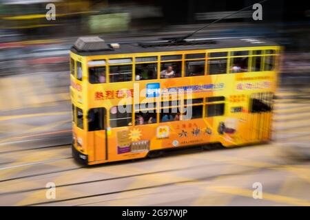 Eine Straßenbahn fährt entlang der des Voeux Road, Central, Hong Kong Island, in einer Schwenkaufnahme mit selektiven Bewegungsunschärfen aufgrund von Kamerabewegungen Stockfoto