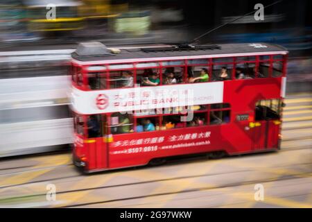 Eine Straßenbahn fährt entlang der des Voeux Road, Central, Hong Kong Island, in einer Schwenkaufnahme mit selektiven Bewegungsunschärfen aufgrund von Kamerabewegungen Stockfoto