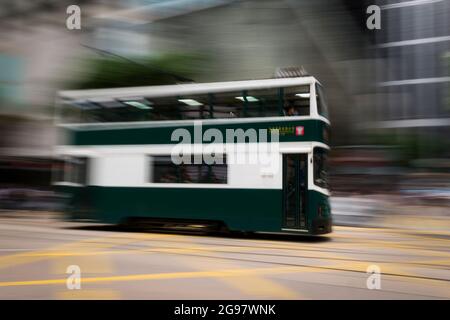 Eine Straßenbahn fährt entlang der des Voeux Road, Central, Hong Kong Island, in einer Schwenkaufnahme mit selektiven Bewegungsunschärfen aufgrund von Kamerabewegungen Stockfoto