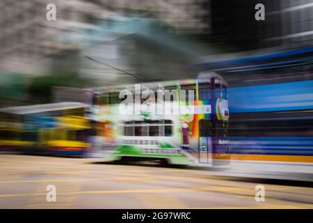 Eine Straßenbahn fährt entlang der des Voeux Road, Central, Hong Kong Island, in einer Schwenkaufnahme mit selektiven Bewegungsunschärfen aufgrund von Kamerabewegungen Stockfoto