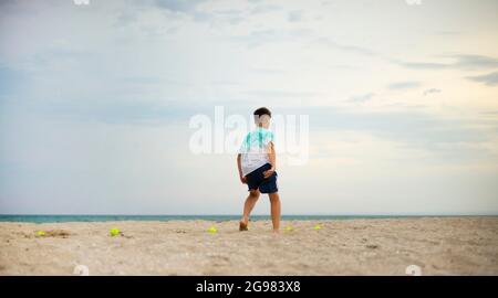 Junge Teenager, die am Sandstrand trainieren. Körperliches Training. Training zur Beinkoordination. Tennisbälle. Stockfoto