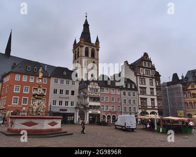 Blick auf den Marktplatz Hauptmarkt mit Wochenmarkt in der Altstadt von Trier am bewölkten Sommertag mit Brunnen und dem Kirchturm der Katholiken. Stockfoto