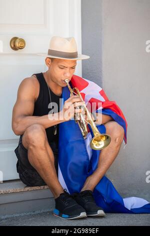 Nahaufnahme eines Latino-Mannes mit kubanischer Flagge, die Trompete spielt Stockfoto