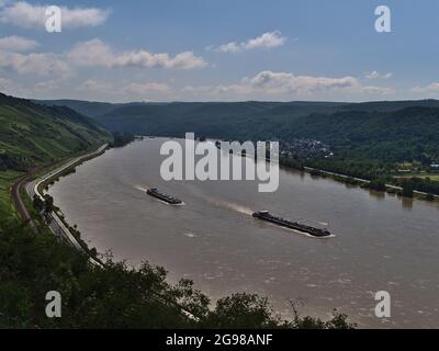 Schöne Aussicht auf den Rhein, eine wichtige Binnenschifffahrt, mit zwei vorbeifahrenden Schiffen und Weinbergen und Wäldern in der Umgebung. Stockfoto