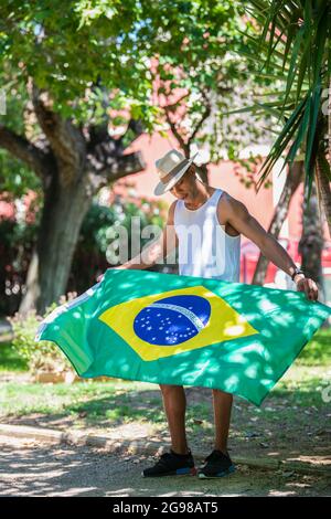 Latino-Mann mit einem Hut, der in Brasilien Flagge fliegt: Selektiver Fokus. Diversity-Konzept. Stockfoto