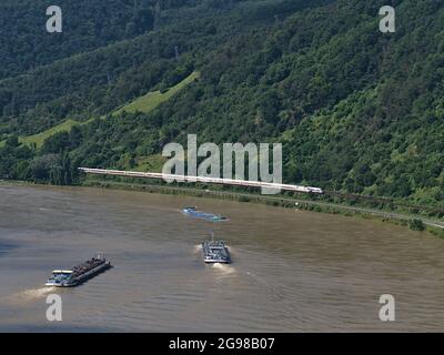 Luftaufnahme des Rheins, einer wichtigen Binnenschifffahrt, mit drei Frachtschiffen und zwei ICE-Zügen, die an sonnigen Tagen vorbeifahren. Stockfoto