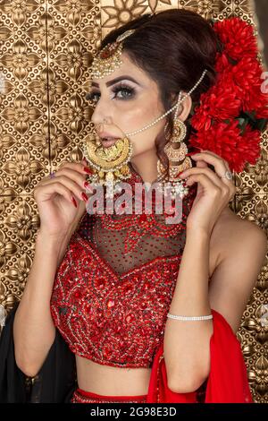 Schöne asiatische Braut in rotem Kleid im Salon Stockfoto