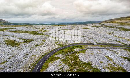 Luftaufnahme einer Straße, die durch den Burren in West-Irland führt, die aus Kalkstein bedeckten Bergen besteht. Stockfoto