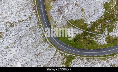 Luftaufnahme eines Blickes auf eine Straße, die durch den Burren im Westen Irlands führt, die kalkbedeckte Berge ist. Stockfoto
