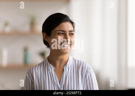 Lächelnde, verträumte indische Frau mit Kopfschuss, die zur Seite schaut Stockfoto