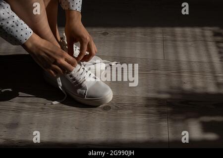 Frau zog neue weiße Leder-Sneakers an Stockfoto