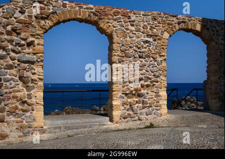 Diese Strecke von restaurierten Schutt Wand auf der Piazza Marina, über dem Alten Hafen und Marina Beach in Cefalu, Sizilien, Italien, war Teil der mittelalterlichen Befestigungsanlagen, die einst die Stadt umgab. Die beiden runden Bögen bieten einen Blick auf das Tyrrhenische Meer und den Zugang zum Sentiero sugli Scogli (Pfad auf den Felsen), der einen detaillierten Blick auf viel ältere Festungen und ‘Megalith’ Mauern aus dem 5. Jahrhundert v. Chr. ermöglicht, um Seeangriffe zu verhindern. Riesige Blöcke des lokalen Lumachella- oder Feuermarmorgesteins werden bis zu fünf bis sechs Meter (16 bis 20 Fuß) hoch gestapelt. Stockfoto