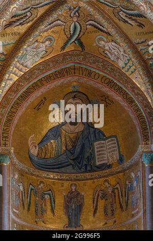 Christus Pantokrator oder Allmächtiger Christus in byzantinischem Mosaik in Apsis Halbkuppel des Duomo di Cefalù in Sizilien, Italien. Das Mosaik wurde von dem normannischen König von Sizilien Roger II. (1095–1154) in Auftrag gegeben und Mitte des 12. Jahrhunderts n. Chr. von Meister-Mosaiken aus Konstantinopel geschaffen. Ein kolossaler, allmächtiger Jesus Christus, prächtig in Blau und Gold gekleidet, segnet die Gemeinde, während er ein offenes Buch hält. Unter Christus befinden sich seine Mutter, die Heilige Maria, und vier Erzengel, die byzantinisches Hofkleid tragen. Über Christus sind Cherubim und Seraphim. Stockfoto