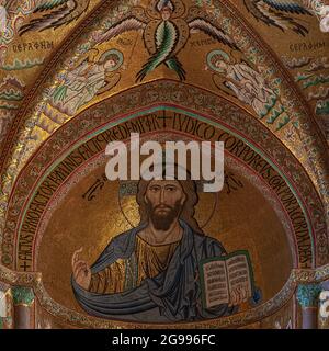 Christus Pantocrator in der Kathedrale in Cefalu, Sizilien, Italien. Quadratisches Detail des 1100s byzantinischen goldenen Apfelmosaiks von Meistermosaiken aus Konstantinopel, im Auftrag des normannischen Königs von Sizilien, Roger II. (1095-1154). Während Christus seine rechte Hand in einer Geste des Segens erhebt, hält seine linke Hand ein offenes Buch mit griechischem und lateinischem Evangelium Text von Johannes 8:12: "I am the light of the world. Wer mir folgt, wird nicht im Dunkeln gehen, sondern das Licht des Lebens haben.“ Stockfoto