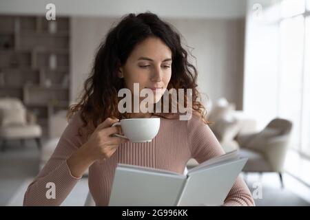 Junge Latino Frau lesen Buch trinken Tee Stockfoto