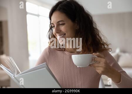 Lächelnde hispanische Frau genießen das Wochenende mit Buchlesung Stockfoto