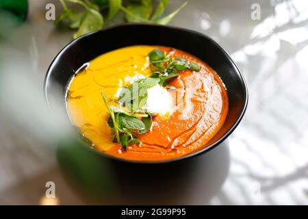 Gelbe, cremige Kürbis- und Karottensuppe. Diätetische gelbe Gemüsesuppe. Gericht auf einem Teller, Food-Fotografie, Serviervorschlag. Stockfoto
