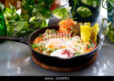 Shakshouka, Spiegeleier in einer Pfanne mit Gemüse und Tomaten. Frühstück, Eier mit Gemüse in einer Pfanne serviert. Stockfoto