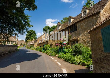 Cotswold Cotswold Cottages und Pink Roses auf der Straße durch Snowshill Village, Gloucestershire, England Stockfoto