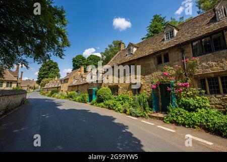 Cotswold Cotswold Cottages und Pink Roses auf der Straße durch Snowshill Village, Gloucestershire, England Stockfoto