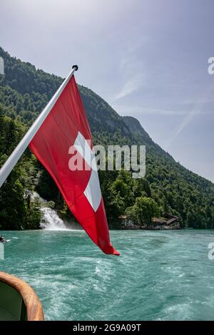 Die Schweizer Flagge mit schönen Giessbach-Wasserfällen - Blick vom Dampfschiff im Brienzersee, Schweiz Stockfoto