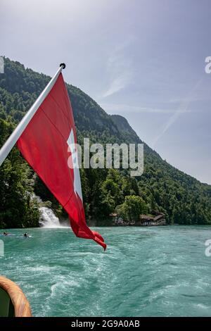 Die Schweizer Flagge mit schönen Giessbach-Wasserfällen - Blick vom Dampfschiff im Brienzersee, Schweiz Stockfoto