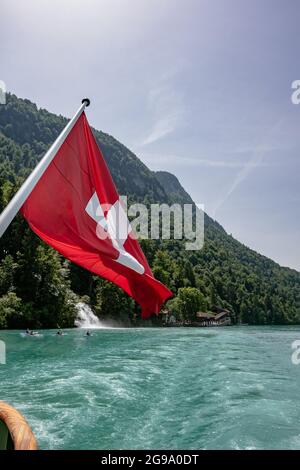 Die Schweizer Flagge mit schönen Giessbach-Wasserfällen - Blick vom Dampfschiff im Brienzersee, Schweiz Stockfoto