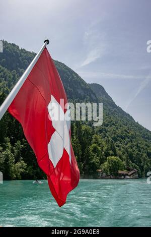 Die Schweizer Flagge mit schönen Giessbach-Wasserfällen - Blick vom Dampfschiff im Brienzersee, Schweiz Stockfoto