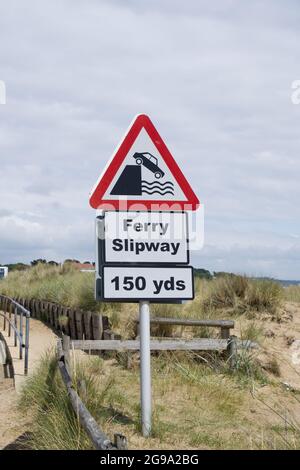 Dreieckiges Warnschild mit Auto fällt in Wasser Fähre Slipway 150 Yds gegen Sanddünen und Meer bei Shell Beach Poole Dorset UK Stockfoto