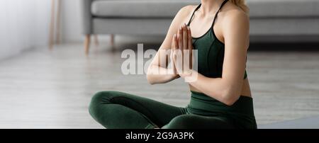 Junge blonde, gesunde, schöne Frau in Sportkleidung, die zu Hause Yoga praktiziert und in Lotuspose sitzt Stockfoto