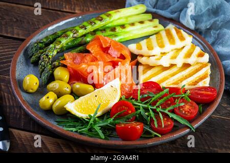 Salat mit Spargel, gegrilltem Halloumi-Käse, Lachsfilet, Tomaten, Rucola und grünen Oliven Stockfoto
