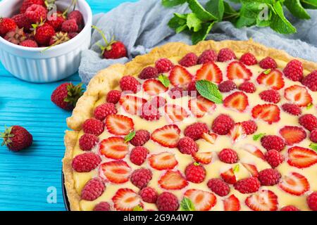 Köstliche hausgemachte Tarte mit Erdbeeren und Himbeeren garniert Minzblätter auf Holz Hintergrund Stockfoto