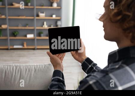 Mann, Der Tablet-Computer Mit Leerem Bildschirm Verwendet, Der House Indoors Steuert Stockfoto