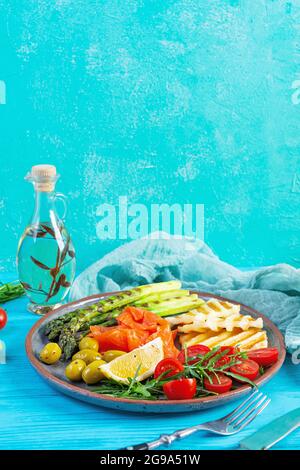 Salat mit Spargel, gegrilltem Halloumi-Käse, Lachsfilet, Tomaten, Rucola und grünen Oliven Stockfoto