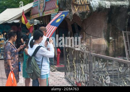 21. August 2017. Gombak, Malaysia. Eine Gruppe von Touristen, die ein Bild eines langschwanzigen Makaken machen, der auf einem Geländer in Bata-Höhlen in Gombak sitzt, se Stockfoto