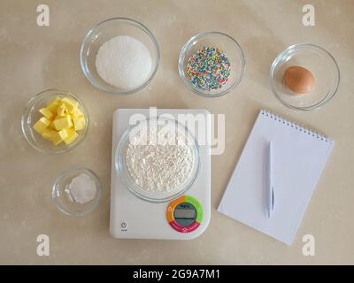 6 Schüssel mit Zutaten, Notizblock und Stift, digitale Küchenwaage Stockfoto