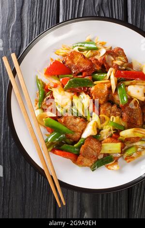 Zweimal gekochtes Schweinefleisch oder doppelt gekochtes Schweinefleisch ist ein chinesisches Gericht gehören Schweinefleisch und gebratenes Gemüse in der Nähe auf dem Teller auf dem Holztisch. Vertikal zu Stockfoto