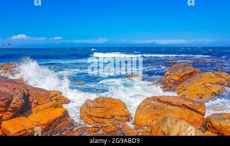 False Bay raue Küstenlandschaft mit Felsbrocken Wellen und Berge mit Wolken in Glencairn Simons Town Kapstadt Westkap Südafrika. Stockfoto