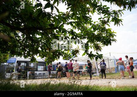 Festivalbesucher stehen beim Latitude Festival in Henham Park, Southwold, Suffolk, an einem Covid-19-Impfbus Schlange. Bilddatum: Sonntag, 25. Juli 2021. Stockfoto