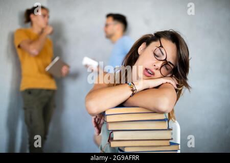 Müde Studentin, die in den Büchern in der Bibliothek schläft Stockfoto