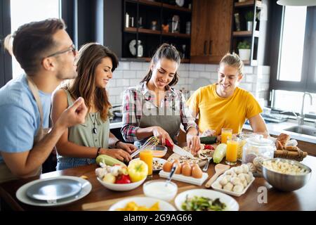 Junge Gruppe von Freunden, die Gemüsemahlzeit zubereiten und Spaß machen. Stockfoto