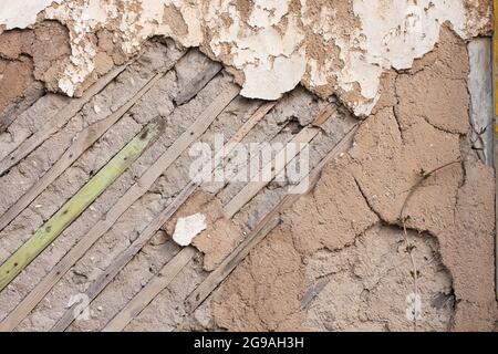 Fragment einer alten zerstörten Mauer mit abgefallener Putze und Holzlatte im verlassenen Haus. Nahaufnahme Stockfoto