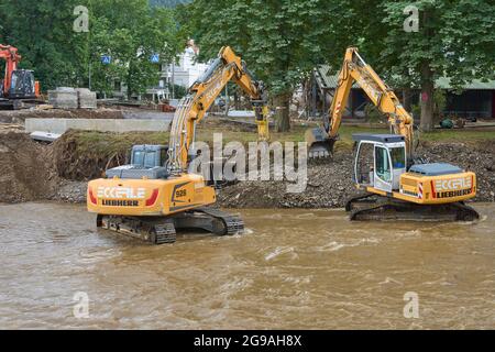 Bad Neuenahr Ahrweiler, Deutschland. Juli 2021. Bagger reißen Teile einer von der Flut zerstörten Brücke über die Ahr nieder und bereiten sich auf den Bau einer provisorischen Brücke vor. Im Ahrtal, das durch die Überschwemmungen schwer verwüstet wurde, werden die Sanarbeiten unvermindert fortgesetzt. Quelle: Thomas Frey/dpa/Alamy Live News Stockfoto