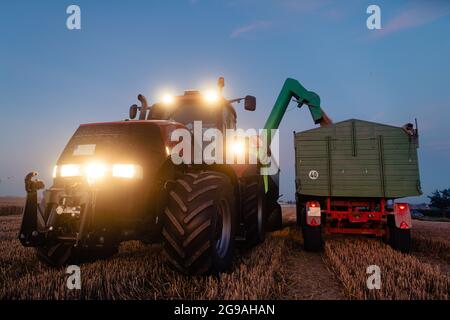 Traktor auf geerntetem Getreidefeld in der Dämmerung Stockfoto