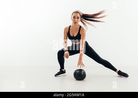 Junge fit Frau in Sportkleidung macht Aufwärmübungen mit einem Medizinball Stockfoto