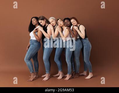 Die ganze Länge von sechs Frauen steht einer nach dem anderen mit geschlossenen Augen. Seitenansicht verschiedener Weibchen, die sich umarmen. Stockfoto