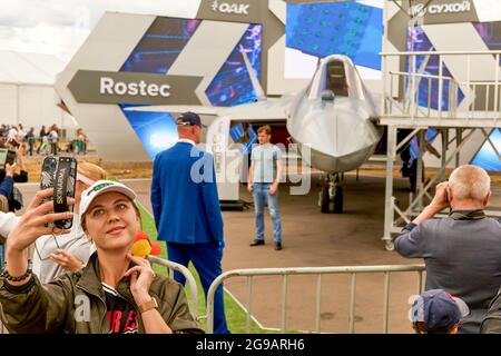 24. Juli 2021, Zhukovsky, Russland: Das Mädchen macht ein Selfie vor dem Hintergrund der Su-57. Ein großes Programm für die 15. MAKS-Flugshow wurde von den Kunstflugteams ''Russian Knights'', ''Swifts'', ''Falcons of Russia''' und ''berkuts'', die die Luftwaffe der Russischen Föderation repräsentieren, vorbereitet. Die Piloten des russischen First Flight Kunstflugteams und natürlich die Gäste aus Indien - das SARANG Hubschrauber Kunstflugteam - nahmen ihr Flugzeug über Schukowski in den Himmel. (Bild: © Mihail Siergiejevicz/SOPA Images via ZUMA Press Wire) Stockfoto